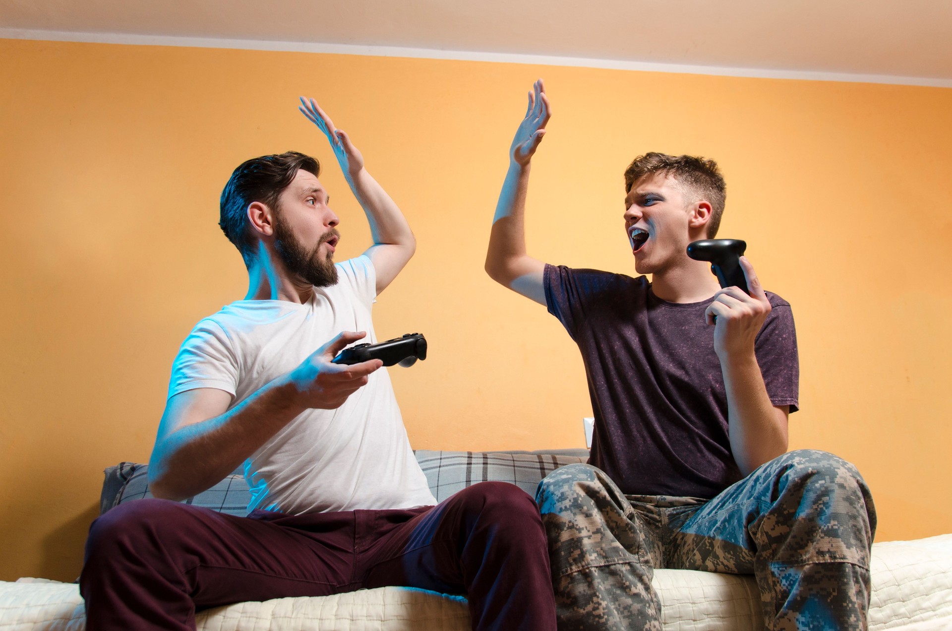 man and teenager giving high five while playing video games